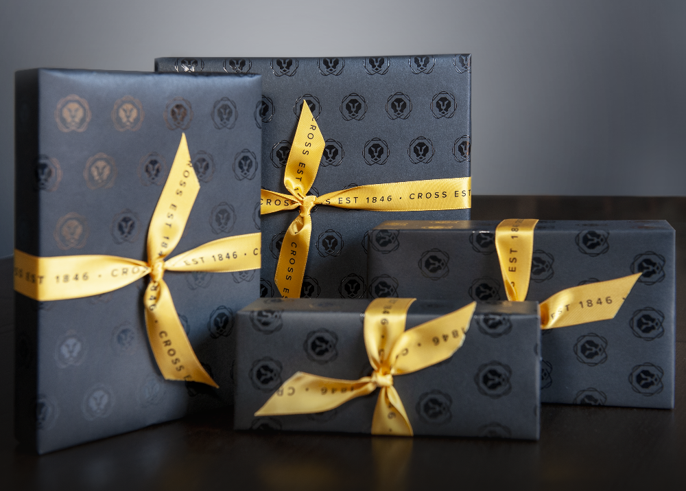 Set of black gift boxes with gold ribbons on a dark surface and gray background